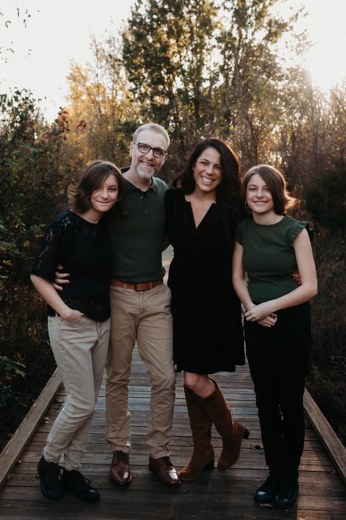 The Colburn family — Jennifer, Mike, and their daughters — on a boardwalk in autumn